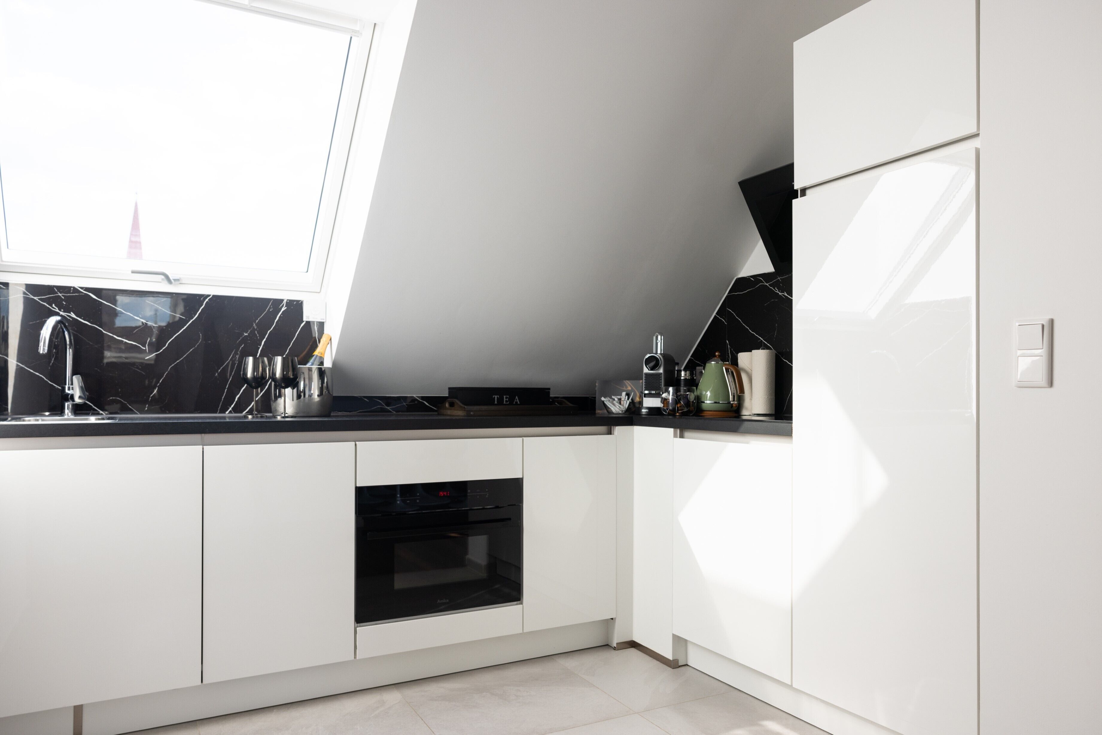 A modern kitchen with white cabinets, a black countertop, and a built-in oven.