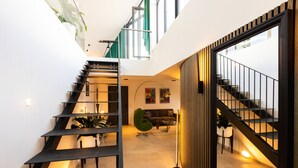 A modern interior with a staircase, a green chair, and a sofa in a well-lit space. - Penthouse at Eco Smart Apartments (Nuremberg)