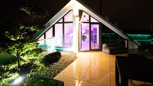 A modern house with a sloped roof, large glass windows, and a well-lit interior. - Penthouse at Eco Smart Apartments (Nuremberg)