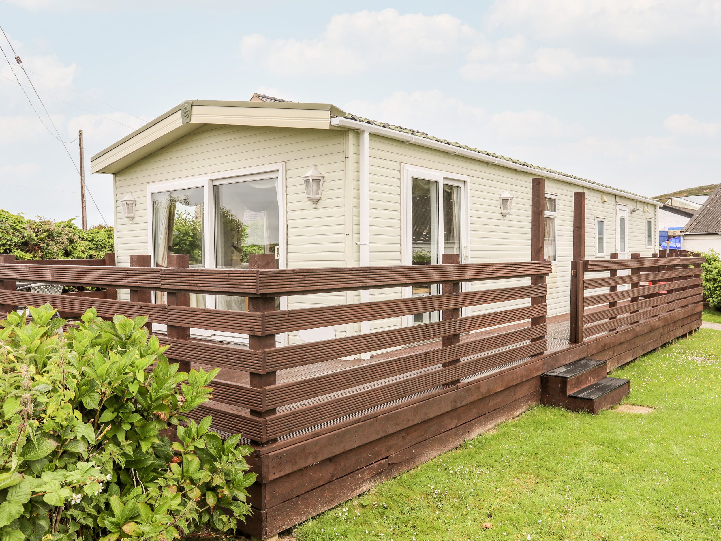 A mobile home with a wooden deck and a small porch.