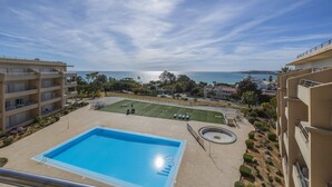 Une piscine avec vue sur la mer, un court de tennis et un jardin aménagé.