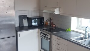 A compact kitchen with white cabinets, a stainless steel refrigerator, a microwave, a stove, and a sink. - 2-bedroom apartment in central Oslo. Located right next to Løren subway (Oslo)