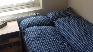 A bedroom with a bed, a window, a radiator, and a small wooden nightstand. - 2-bedroom apartment in central Oslo. Located right next to Løren subway (Oslo)