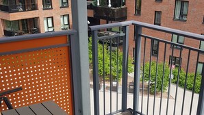 A balcony with a metal table and chairs, a wooden fence, and a view of a brick building with multiple windows and balconies. - 2-bedroom apartment in central Oslo. Located right next to Løren subway (Oslo)
