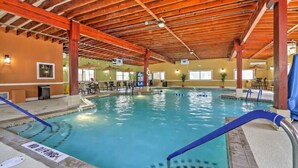 Une piscine intérieure avec des poutres en bois, un revêtement de sol carrelé et un panneau indiquant qu’il est interdit de plonger.