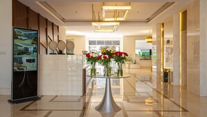 Eine moderne Lobby mit Tischplatte aus Glas, einem digitalen Display und einer Blumenkomposition.