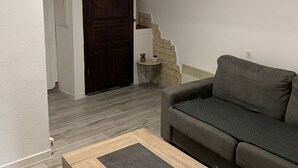 A living room with a grey sofa, a wooden coffee table, and a dark door. - studio 10 minutes from the beach (Olmeta-di-Tuda)