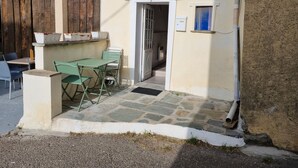 A small outdoor seating area with a table and chairs, a potted plant, and a door leading to a covered entrance. - studio 10 minutes from the beach (Olmeta-di-Tuda)