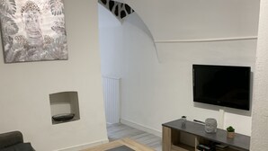 A modern living room with a flat-screen TV, wooden coffee table, and a grey sofa. - studio 10 minutes from the beach (Olmeta-di-Tuda)