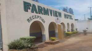 Zona de recepción del Hotel Farmview con un letrero claro, arcos y una pequeña área de jardín con plantas.