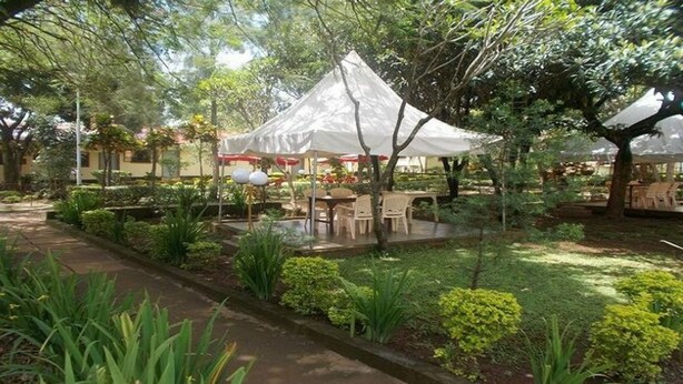 Un jardín con una carpa blanca, mesas y sillas.