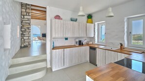 Una cocina moderna con armarios blancos, encimera de madera y vista al mar.