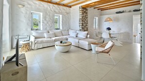 Una sala moderna con un sofá modular, una mesa de centro redonda y una silla de mimbre.