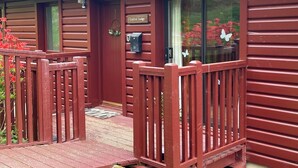 Une cabane en bois à l’extérieur rouge, avec un porche en bois et une boîte aux lettres.