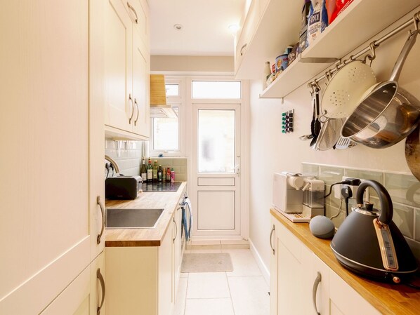 Efficient kitchen with light-colored cabinetry, toaster, and kettle, featuring a window and door to another room.