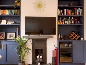 Cozy living room with a large flat-screen TV above the fireplace, dark cabinetry, and a wine rack.