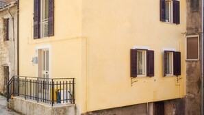 Ein gelbes Gebäude mit Balkon, Tür und kleinem Fenster.