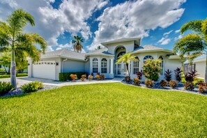 A modern house with a white exterior, a garage, and a well-maintained lawn. - Villa 4Friends, modern, preferred location, heated pool, south facing (Cape Coral)