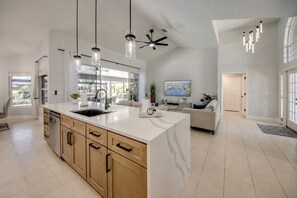 A spacious kitchen with a large island, modern pendant lights, and a ceiling fan. - Villa 4Friends, modern, preferred location, heated pool, south facing (Cape Coral)