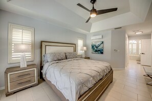 A bedroom with a bed, a nightstand, a ceiling fan, and a window with blinds.