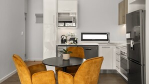 Una cocina moderna con armarios blancos, un refrigerador negro y un comedor con una mesa redonda y sillas amarillas.