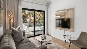Una sala de estar moderna con un sofá gris, una mesa de centro redonda y un televisor de pantalla plana montado en la pared.