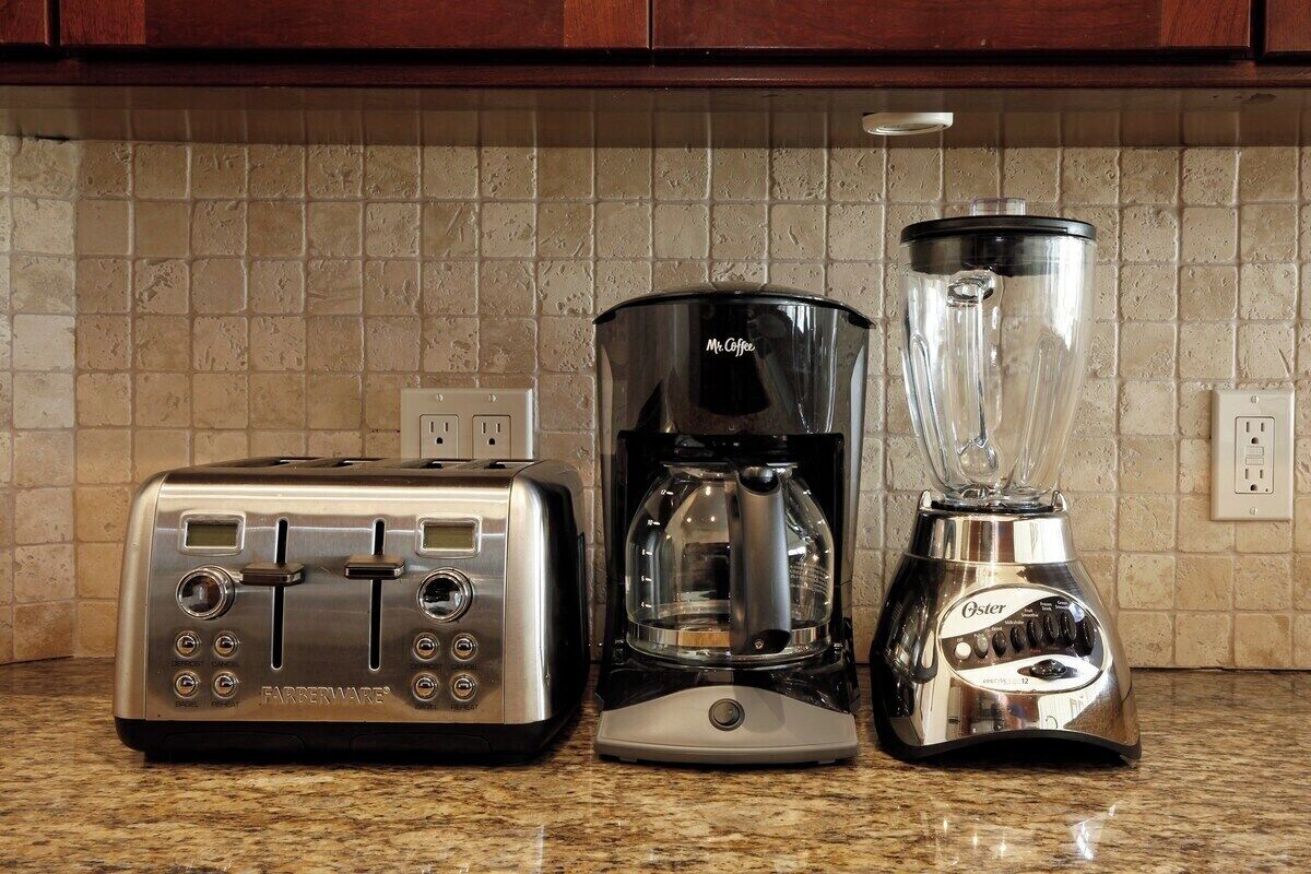 A kitchen with a toaster, coffee maker, and blender on a granite countertop.