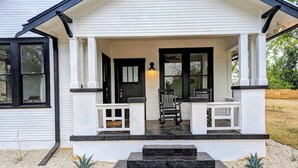 Une maison avec un porche, des marches et un petit jardin.