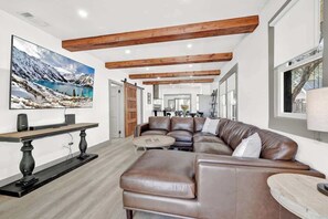 A modern living room with a sectional sofa, a coffee table, and a large painting of a snowy landscape.