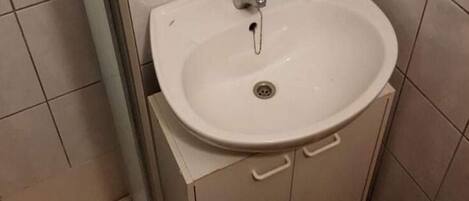 A bathroom with a white sink, a faucet, and a soap dispenser.