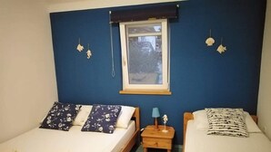 A bedroom with two beds, a window, and a nightstand with a lamp. - Apartments Marija (Pirovac)