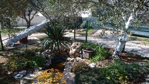 A garden with a variety of plants, a small pond, and a statue. - Apartments Marija (Pirovac)