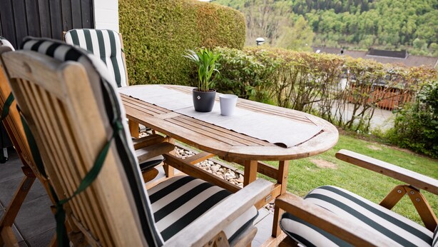 Une table en bois avec des chaises, une plante en pot et une vue sur un paysage verdoyant.