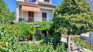 A two-story building with a balcony and a garden in front. - Apartment Lucija (Kastela)