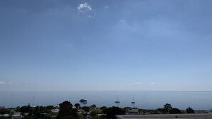 A coastal view with a clear sky, calm sea, and a few boats.