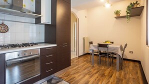 A modern kitchen with a built-in oven, a stove, and a dining area with a table and chairs. - Apartment within walking distance of downtown and the sea (Sorrento)