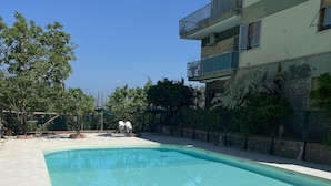 A swimming pool with tiled flooring, surrounded by a fence and trees. - Apartment within walking distance of downtown and the sea (Sorrento)
