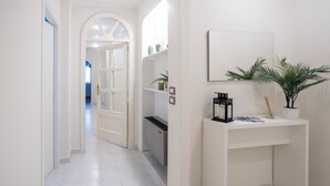 A hallway with a white tiled floor, a white console table with a mirror, and a potted plant. - Apartment within walking distance of downtown and the sea (Sorrento)