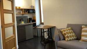 En kompakt bolig med tekøkken, spisebord og sofa.
