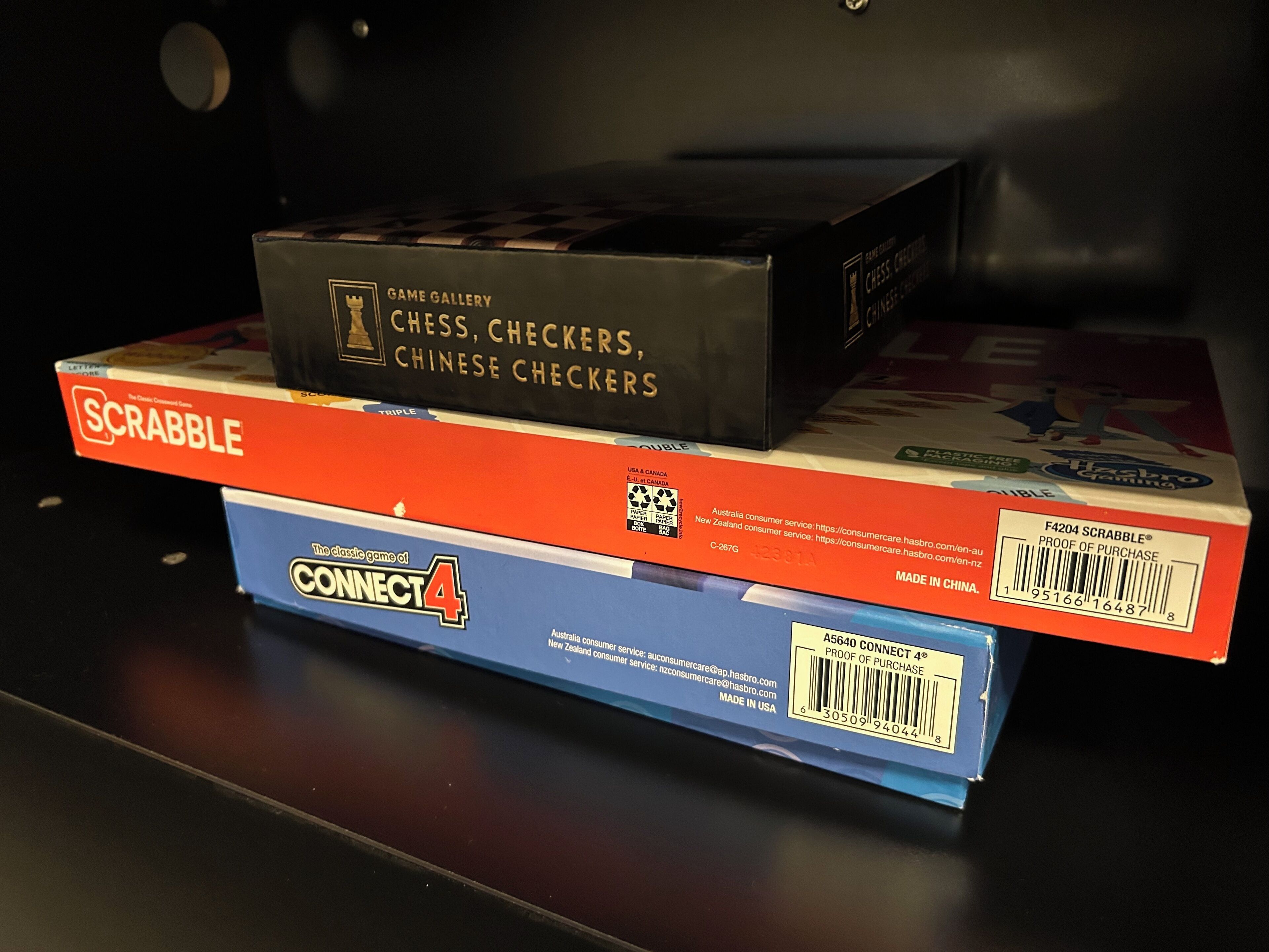 A stack of board games including Scrabble, Connect 4, and Chess Checkers.