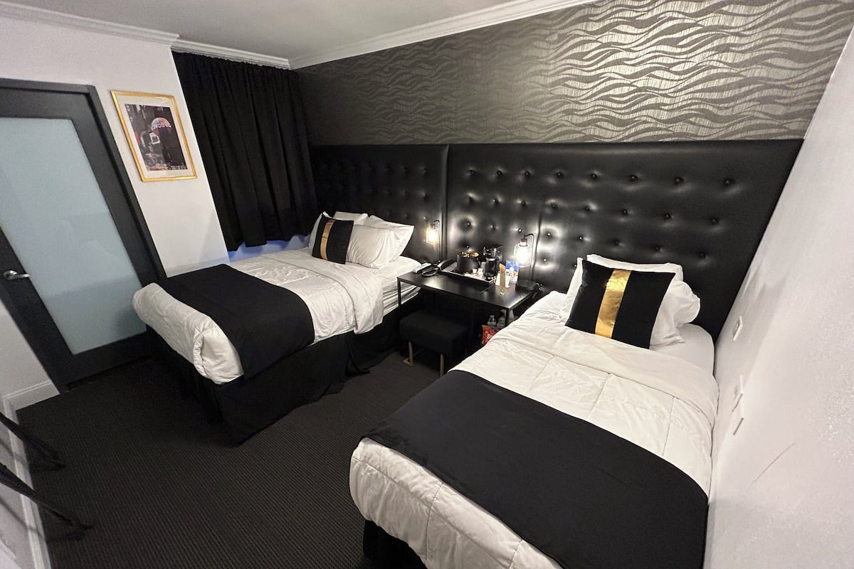 Ett hotellrum med två sängar, ett skrivbord och en stol.