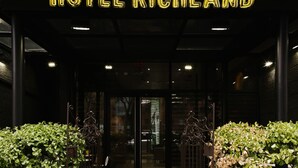 Ingången till Hotel Richland med en neonskylt, en glasdörr och metallgrindar.
