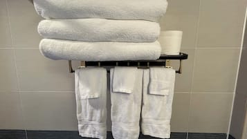 Un baño con un perchero que sostiene toallas dobladas y un rollo de papel higiénico.