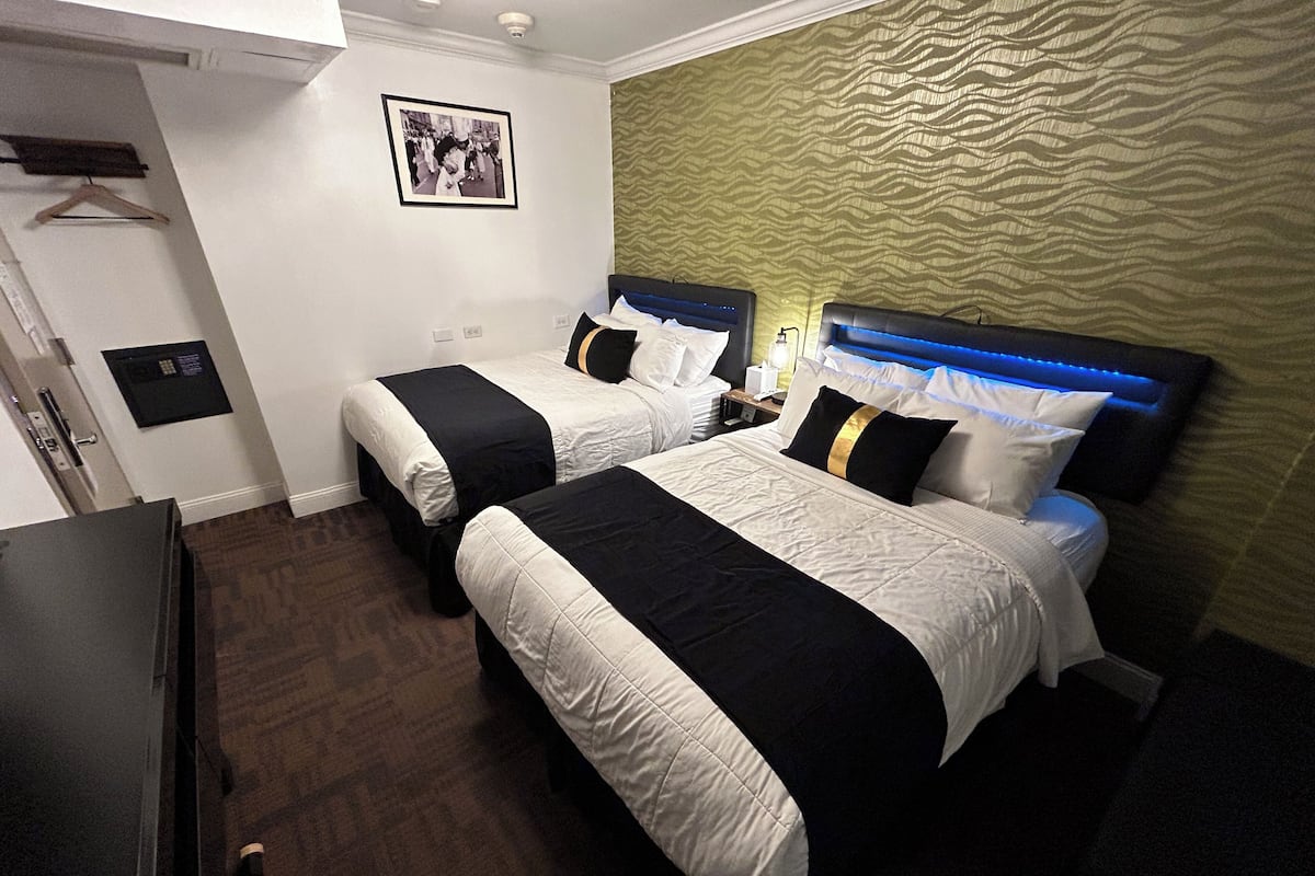 Ett hotellrum med två sängar, en garderob, ett skrivbord och en tavla på väggen.