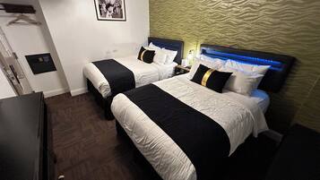 A hotel room with two beds, a wardrobe, a desk, and a picture on the wall.