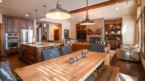 Cocina amplia con armarios de madera, electrodomésticos de acero inoxidable e iluminación colgante.