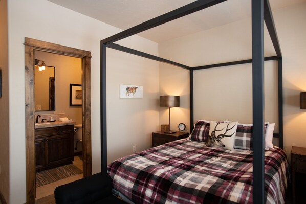 A four-poster bed with a plaid bedspread, a nightstand with a lamp, and a framed picture on the wall. - Lakeside Family Stay with Access to Forest House (Bend)