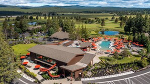 Un resort con piscina, mobiliario exterior y montañas al fondo.