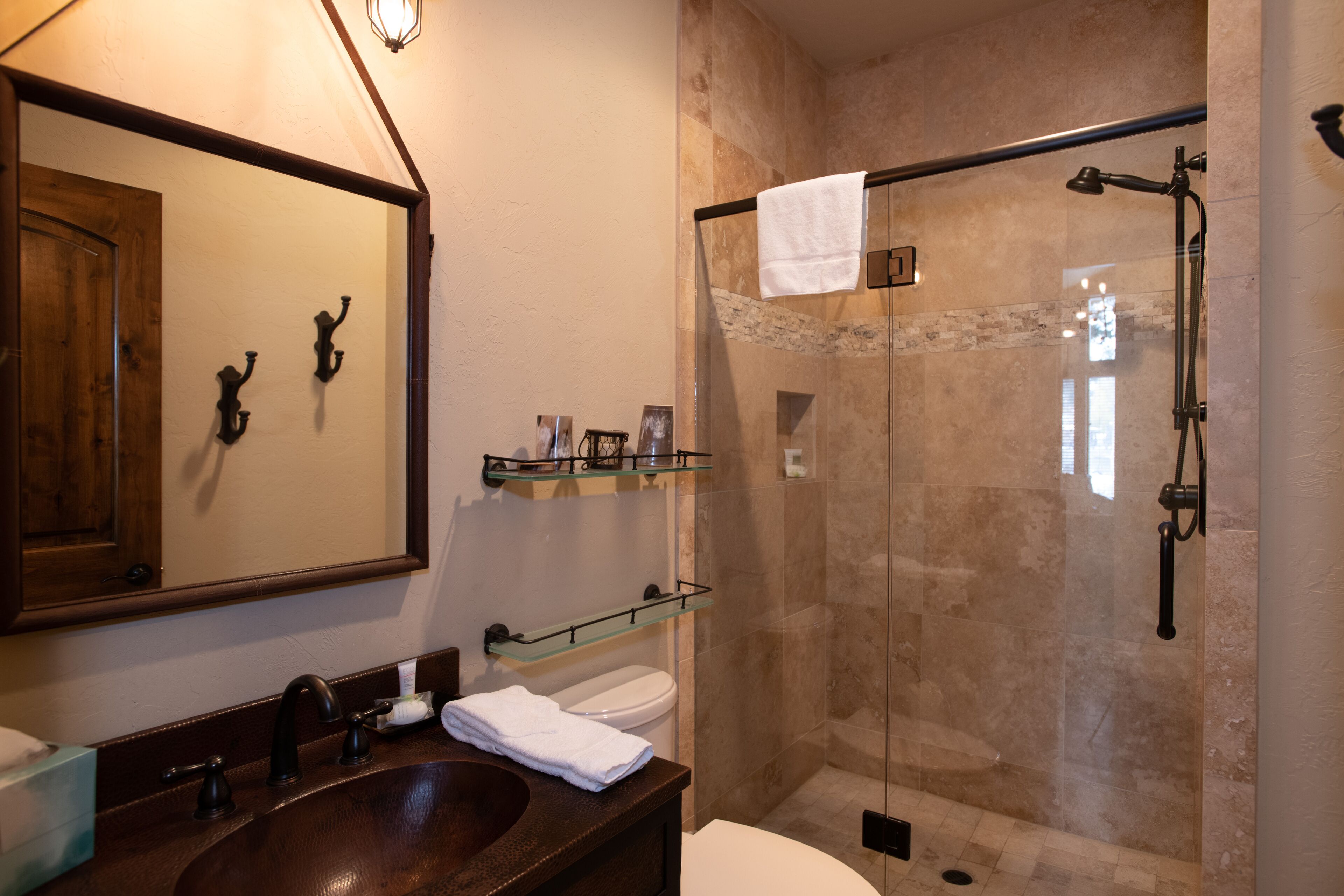 Une salle de bain avec un meuble-lavabo en bois, une cabine de douche en verre et un grand miroir.