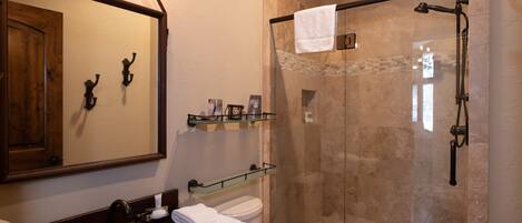 Une salle de bain avec un meuble-lavabo en bois, une cabine de douche en verre et un grand miroir.